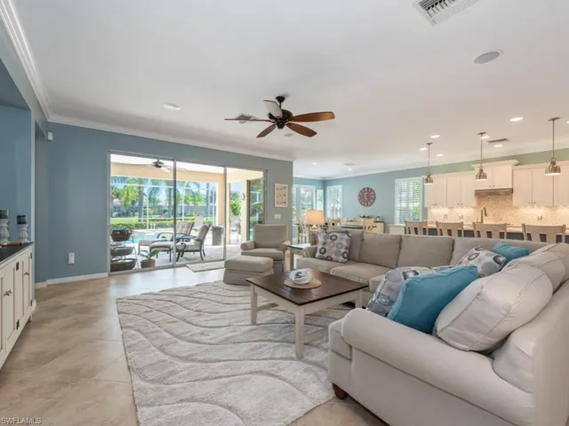 Living room with ceiling fan, crown molding, and light tile floors