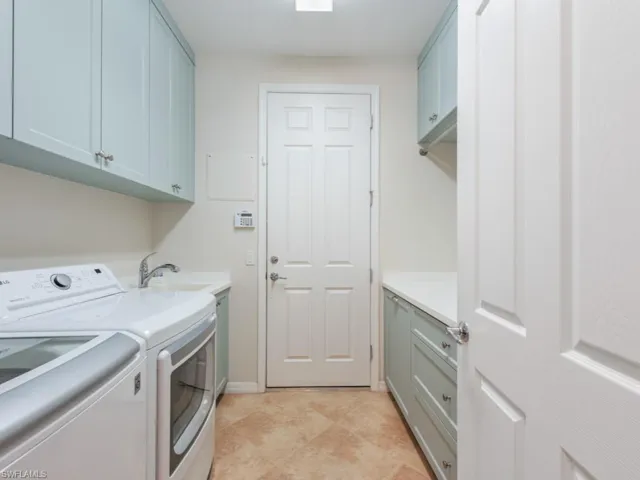 Clothes washing area featuring cabinets, sink, independent washer and dryer, and light tile flooring