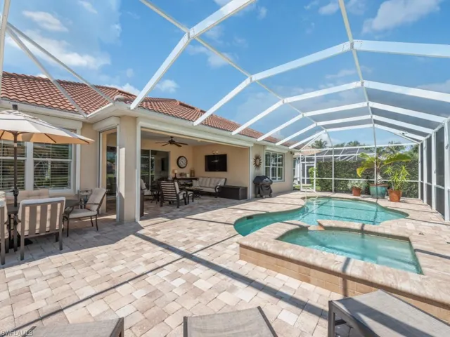 View of pool featuring glass enclosure, an in ground hot tub, a patio area, and ceiling fan