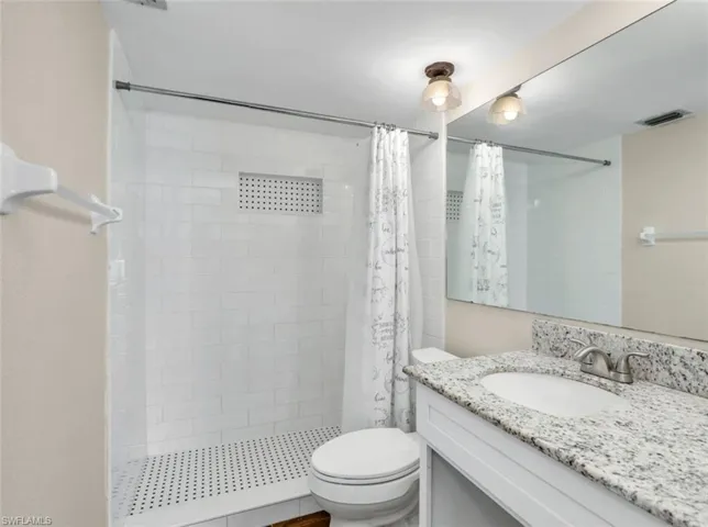 Bathroom with visible vents, a stall shower, toilet, and vanity