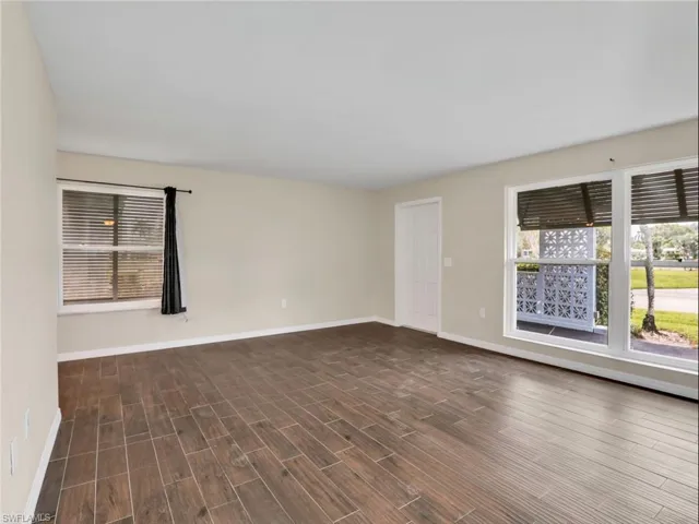 Unfurnished room featuring baseboards and dark wood-style flooring