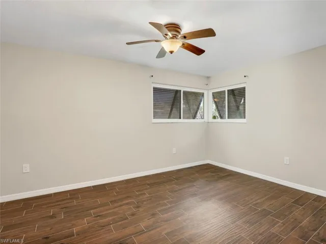 Unfurnished room featuring baseboards, wood finish floors, and a ceiling fan