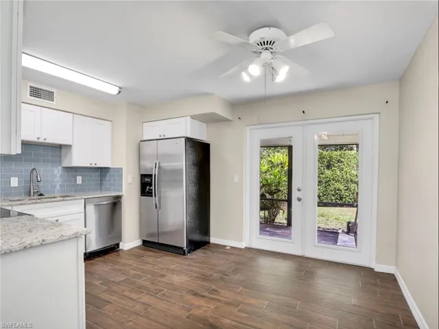Kitchen featuring tasteful backsplash, stainless steel appliances, dark wood-type flooring, a sink, and visible vents