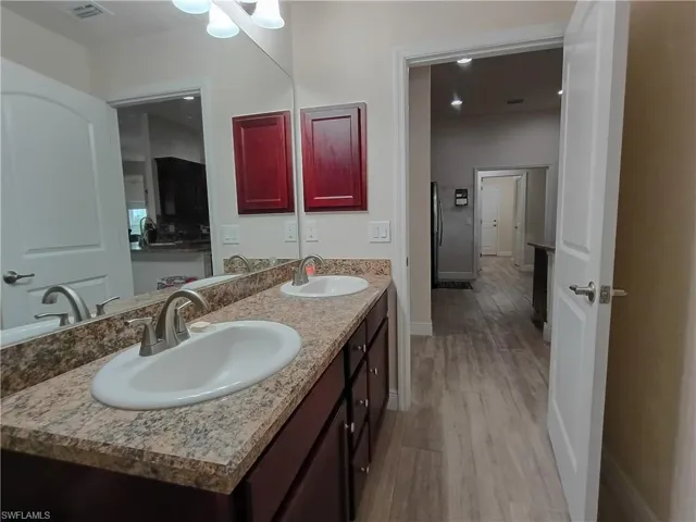 Bathroom with double vanity, light wood-style flooring, and recessed lighting