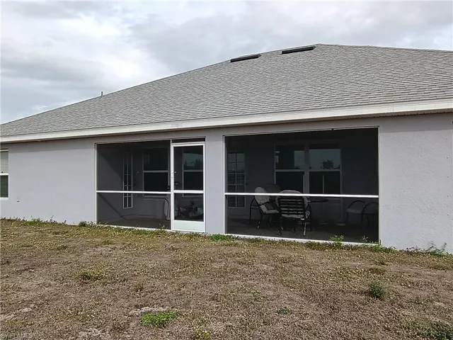 Back of house with stucco siding, a sunroom, and a shingled roof