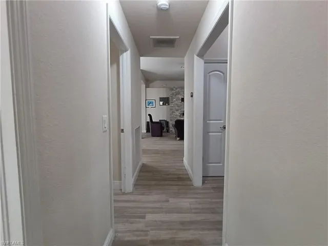 Corridor with a textured wall and light wood finished floors