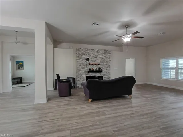 Living room with a fireplace, a ceiling fan, and light wood-style floors