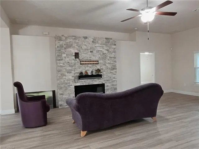 Living room featuring wood finished floors, a fireplace, and a ceiling fan