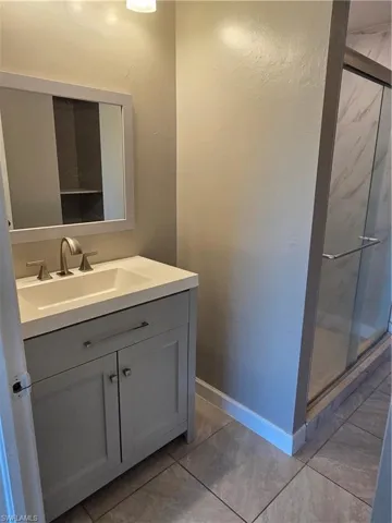 Bathroom with vanity and a marble finish shower
