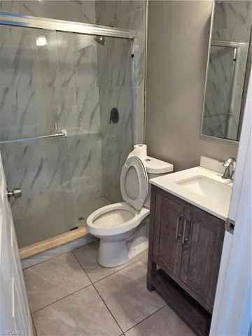 Bathroom featuring vanity and a marble finish shower