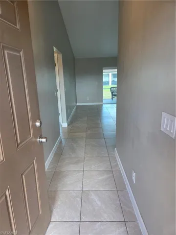 Hall with lofted ceiling and light tile patterned flooring