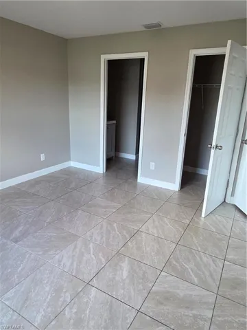 Unfurnished bedroom with a walk in closet and baseboards