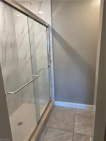 Bathroom featuring a marble finish shower and baseboards