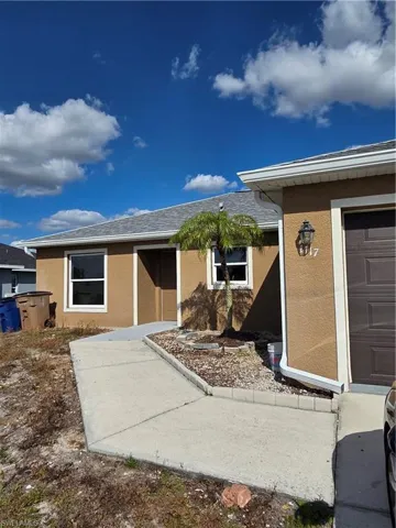 Entrance to property with stucco siding and a shingled roof
