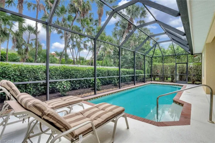 View of pool with screen enclosure and covered outdoor living