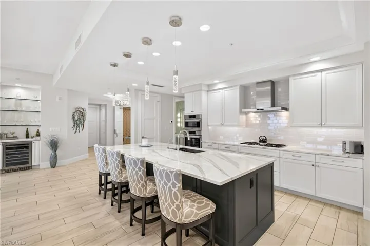 Kitchen featuring a breakfast bar area, decorative light fixtures, white cabinetry, wine cooler, and recessed lighting
