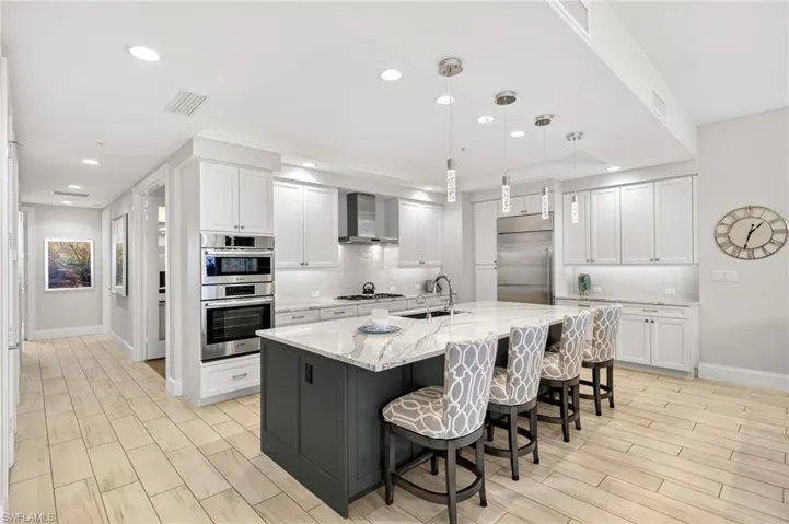 Kitchen featuring white cabinetry, hanging light fixtures, a breakfast bar, wood finish floors, and backsplash