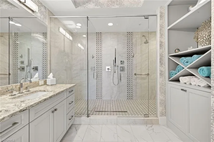 Bathroom with vanity, a stall shower, and light marble finish flooring
