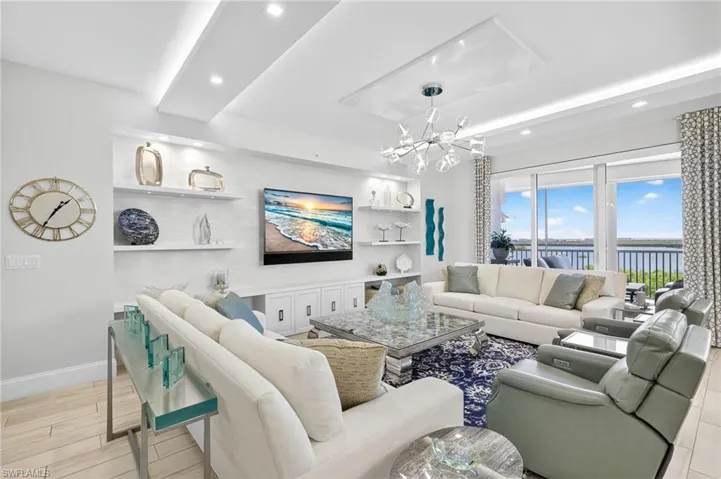 Living area featuring a chandelier, built in shelves, wood finished floors, recessed lighting, and a tray ceiling