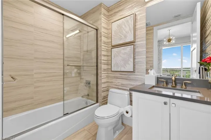 Bathroom featuring combined bath / shower with glass door and vanity