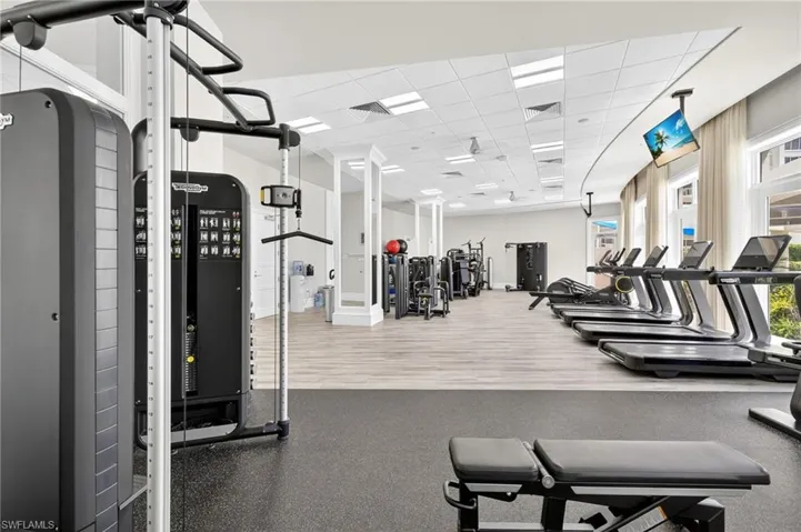 Exercise room with a paneled ceiling and baseboards