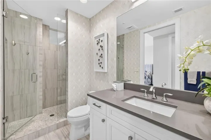 Bathroom with a stall shower, vanity, and recessed lighting
