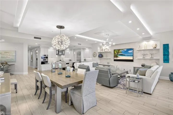 Dining room featuring a chandelier, light wood-type flooring, a raised ceiling, and recessed lighting