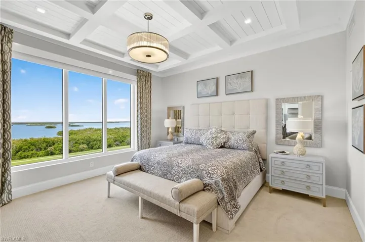 Carpeted bedroom featuring a water view, coffered ceiling, and a wooden ceiling with exposed beams