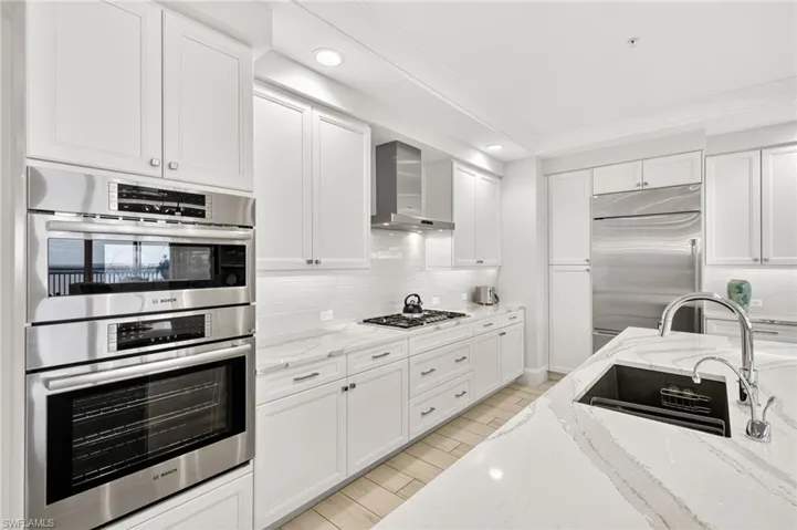 Kitchen with appliances with stainless steel finishes, light stone countertops, white cabinets, decorative backsplash, and recessed lighting
