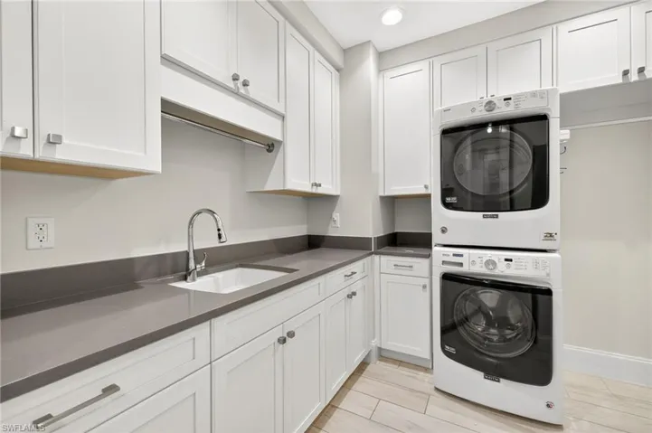 Laundry area with stacked washer and clothes dryer, wood tiled floors, cabinet space, and recessed lighting