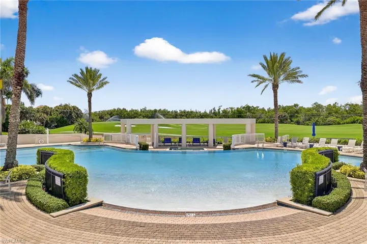 Community pool with a patio area, a yard, and view of wooded area