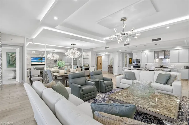 Living area with a chandelier, light wood-type flooring, and a tray ceiling