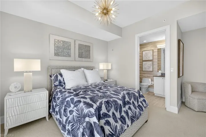 Bedroom with light carpet, a chandelier, and connected bathroom