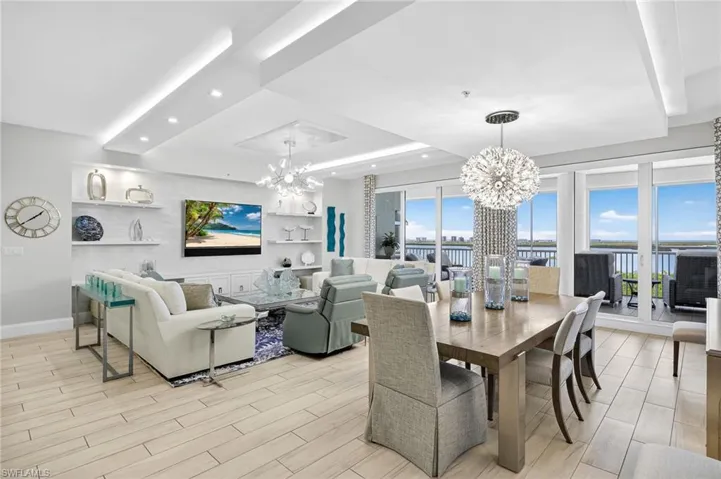 Dining area featuring a raised ceiling, a chandelier, wood tiled floors, healthy amount of natural light, and recessed lighting