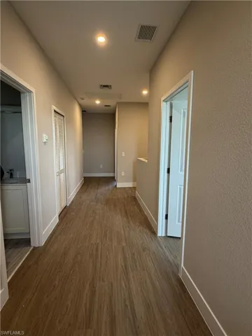 Hallway featuring wood-look flooring, recessed lighting, and a neutral color palette