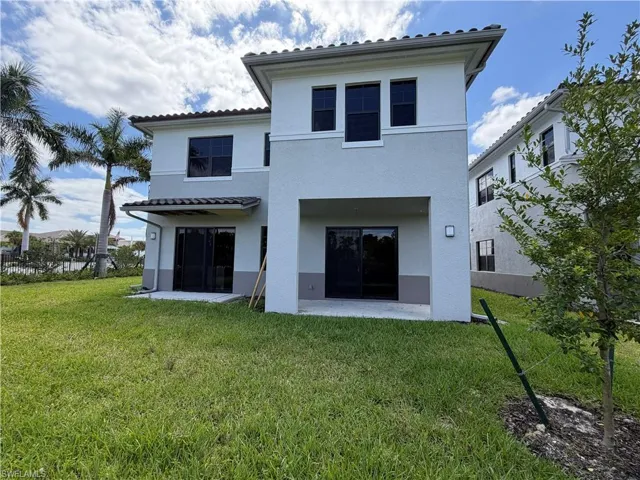 The property features a stucco exterior with a tiled roof and an extensive yard with a lawn