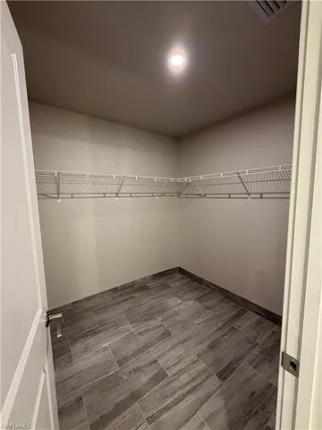 Spacious closet featuring tiled flooring, a ceiling light fixture, and wire shelving