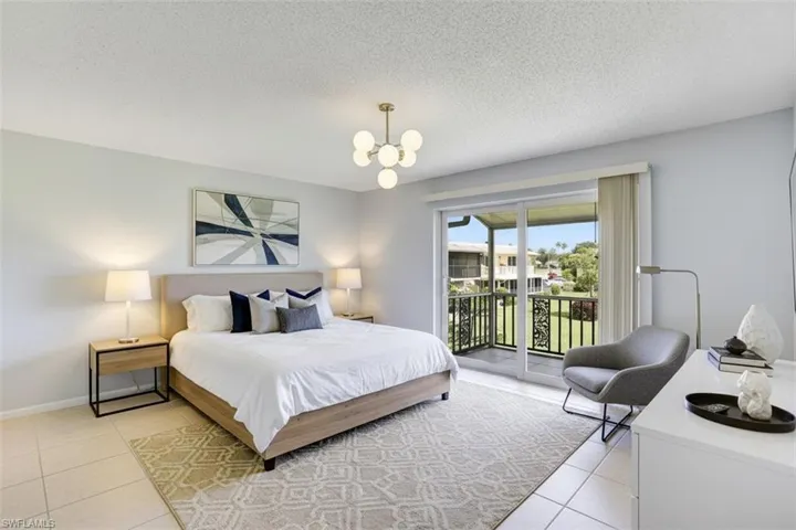 Bedroom - virtual staged - with access to outside, a textured ceiling, light tile patterned floors, and hanging lights
