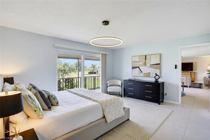 Bedroom - virtual staged - with access to outside, a textured ceiling, and light tile patterned floors