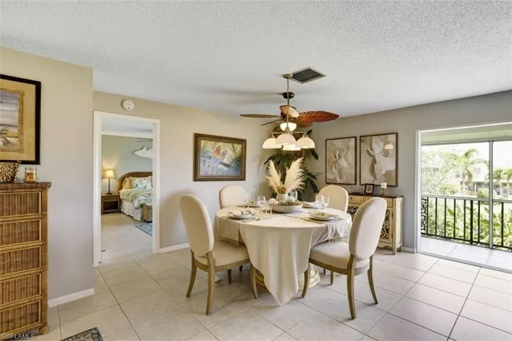 355-Palm-Dr-732-Naples-FL-Dining space partial virtual staged featuring a ceiling fan, a textured ceiling, and light tile patterned floors