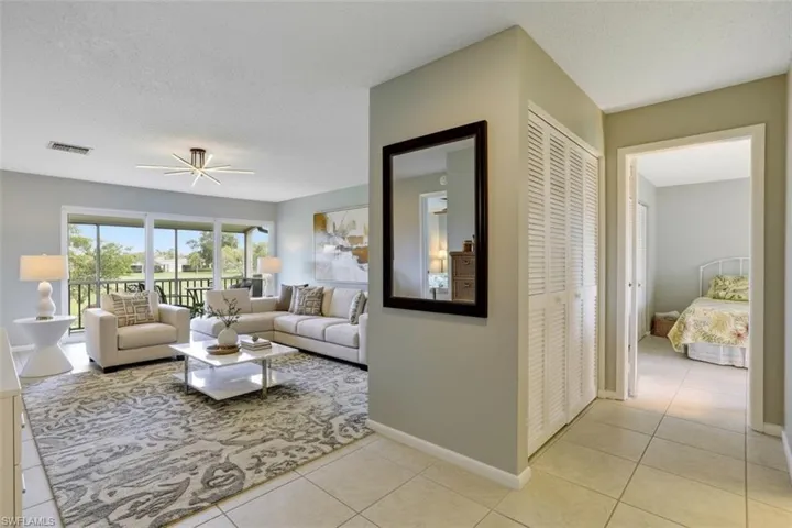 355-Palm-Dr-732-Naples-FL- entry area - virtual staged- with a textured ceiling, light tile patterned floors, and a ceiling fan