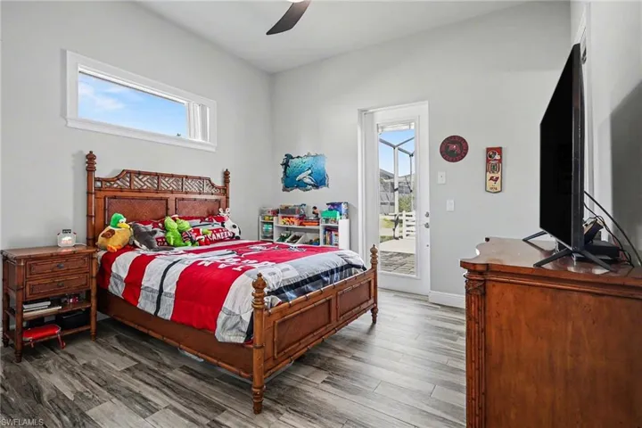 Bedroom with wood finished floors, access to outside, and ceiling fan