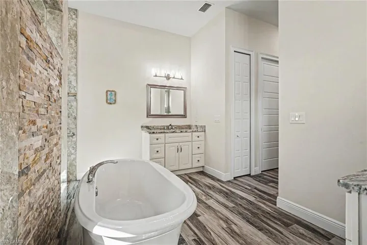 Full bathroom with vanity, a freestanding bath, and dark wood finished floors