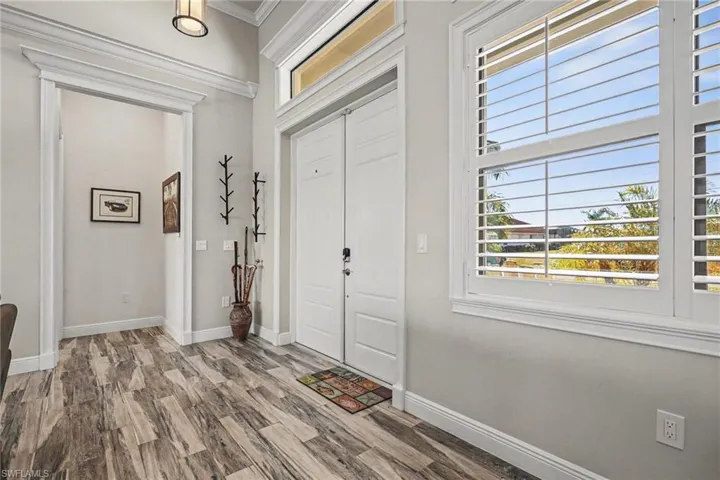 Entryway with wood finished floors and crown molding