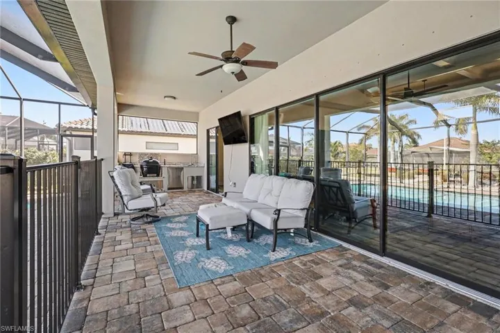 View of patio / terrace featuring glass enclosure, a sunroom, a ceiling fan, grilling area, and an outdoor lounge area