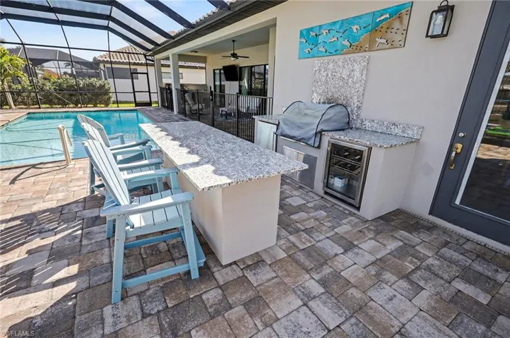 View of patio / terrace with an outdoor kitchen, glass enclosure, a sunroom, and ceiling fan