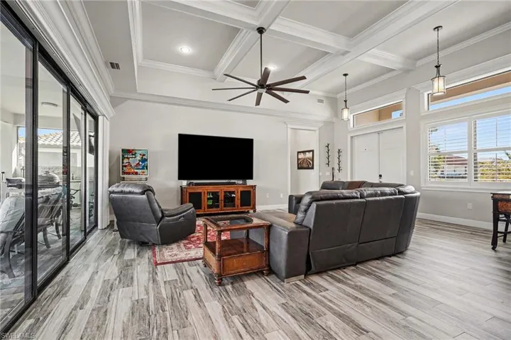 Living room with a ceiling fan, light wood-style flooring, coffered ceiling, recessed lighting, and ornamental molding