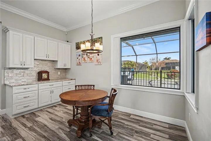 Dining area featuring light wood finished floors, crown molding, and hanging lights