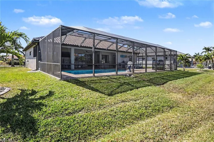 Rear view of property with glass enclosure, an outdoor pool, a sunroom, a yard, and a patio area