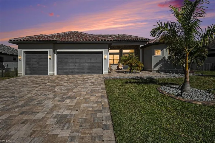 View of front of property featuring a tile roof, a garage, driveway, and stucco siding